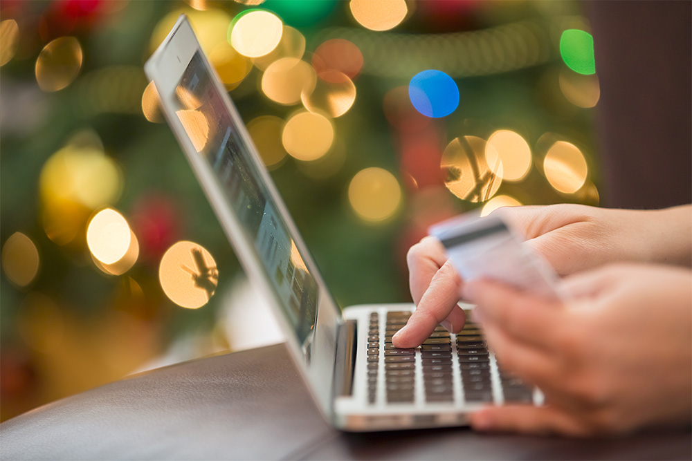 person's hands in front of a laptop holding a credit card