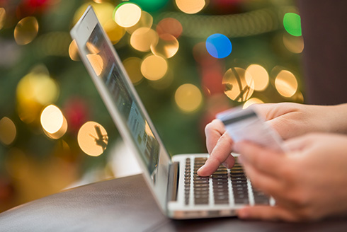 person's hands in front of a laptop holding a credit card