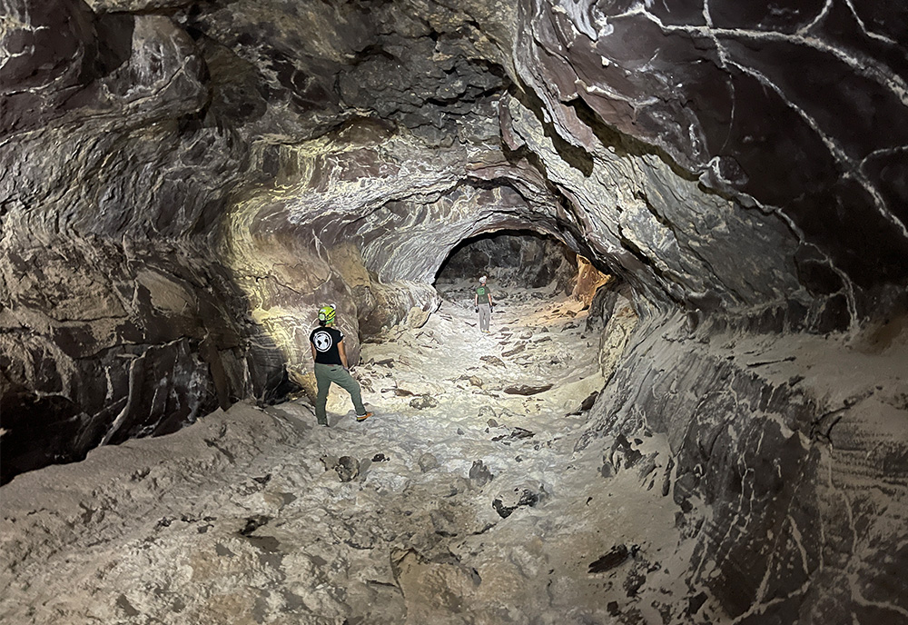 Big view of large lava tube where two researchers are walking through