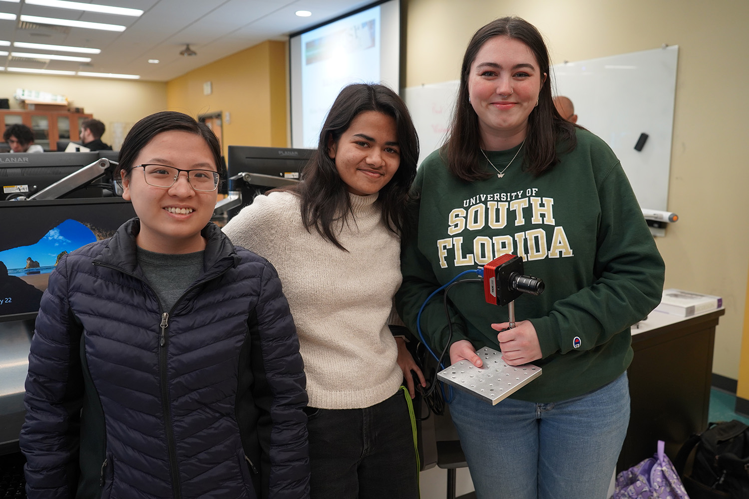 Victoria smiling with her prototype and two research partners