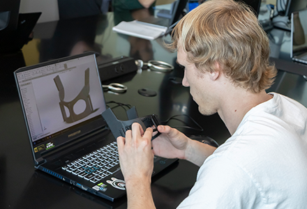 Student in front of computer with medical device