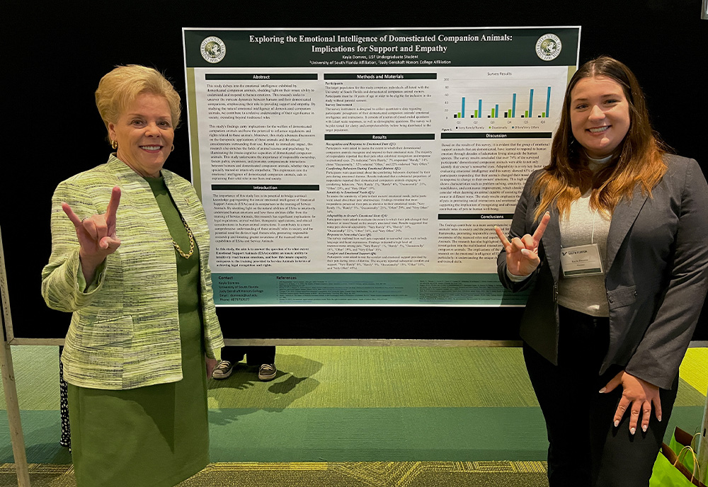 President Law standing with Kayla at her poster board on emotional intelligence in animals