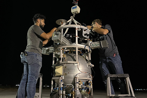 Two men work on a rocket