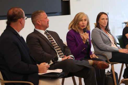 Four GNSI panelists sit in a row while addressing students about their national and international security careers.