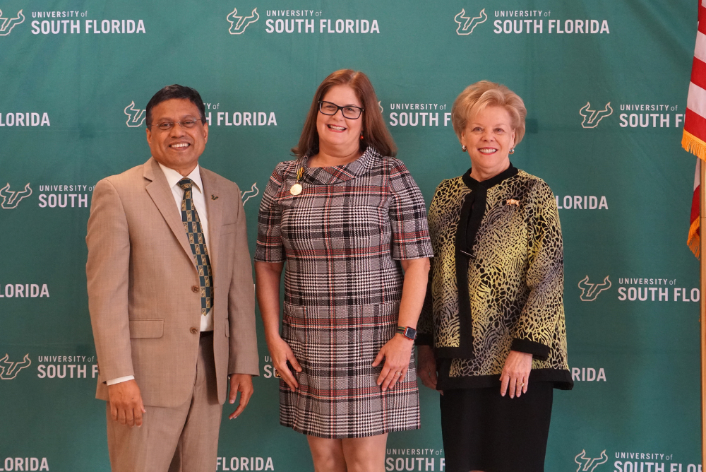 USF Provost Prasant Mohapatra, Professor Judithanne Scourfield McLauchlan, and President Rhea Law pose in front of a University of South Florida step and repeat