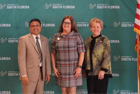 USF Provost Prasant Mohapatra, Professor Judithanne Scourfield McLauchlan, and President Rhea Law pose in front of a University of South Florida step and repeat