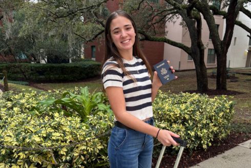 student holding suitcase and passport on USF campus