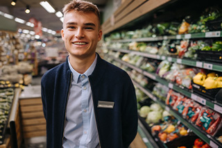 male student working in produce section of major grocery store