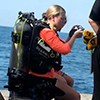 female student with diving tanks puts on face mask
