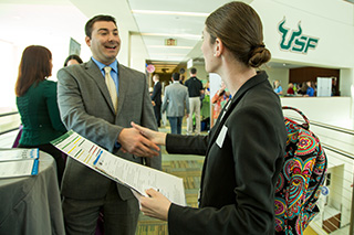 female student shaking hands with a company representative at a USF career fair 