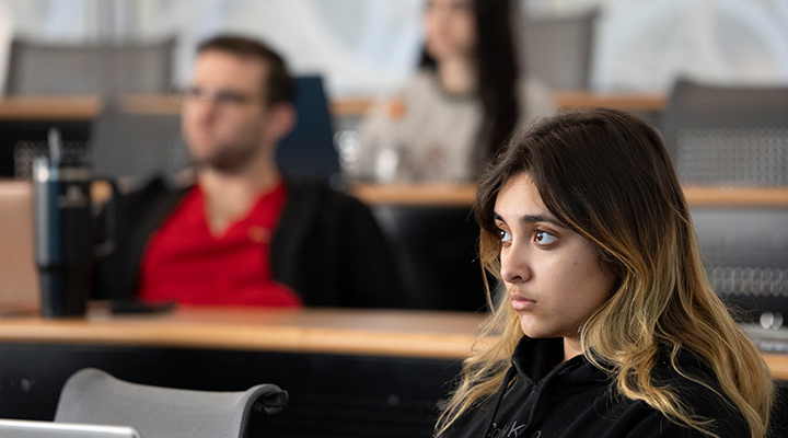 female student sitting in classroom intently listening to lecture
