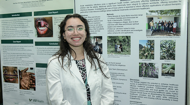 student in front of research poster