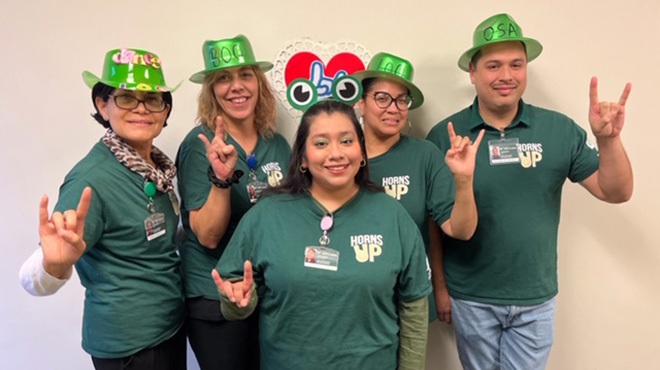 a group of testing services employees pose with their horns up hand sign. 