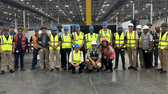 a group of workers in a factory wearing safety hats and vests