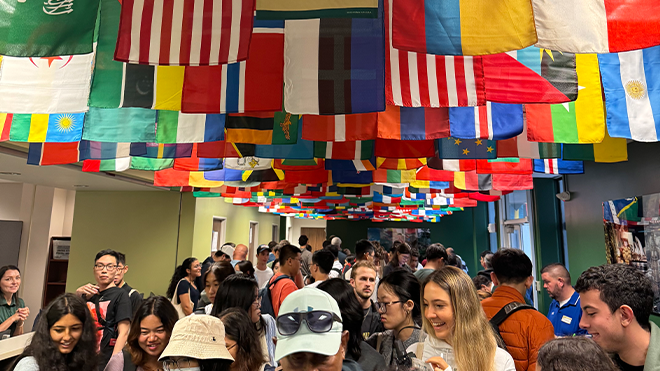 Row of flags hanging from ceiling over a hall full of people