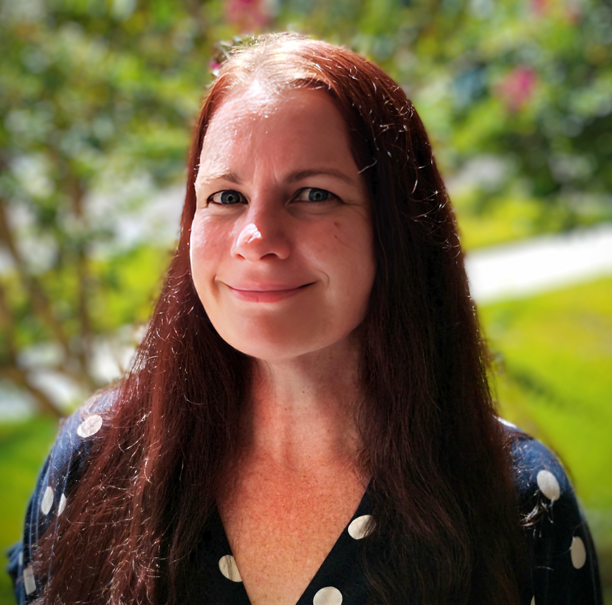 A headshot of a person with long red hair