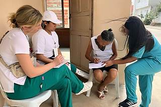 nursing students standing around a colombian woman who is filling out a form