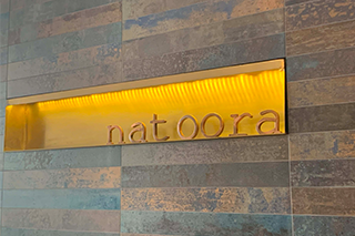 A gold lit sign with the name "natoora"
