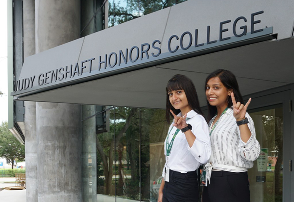 Two people smiling in front of the Judy Genshaft Honors College