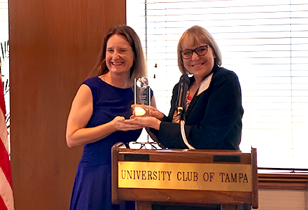 Amanda is recieving an award from another person in a blue dress at a podium