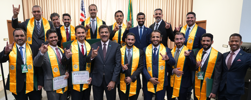 A group of USF graduates with yellow sashes and holding up the "bulls" sign with hands