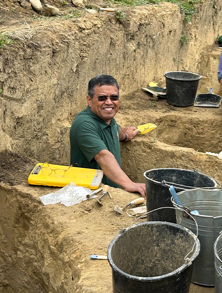 Provost Mohapatra standing in a grave with rubber gloves on