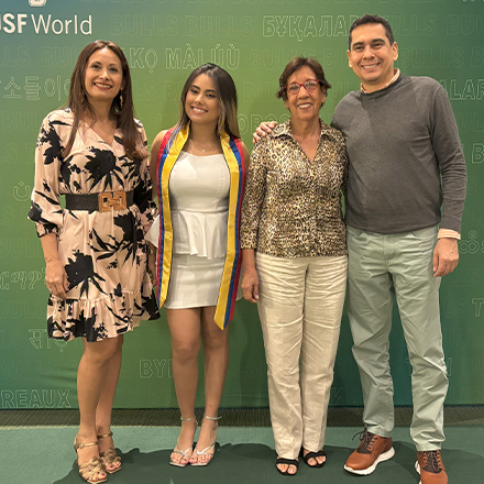 A family smilling in front of a green backdrop