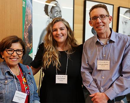 Two women standing beside a man, all smiling