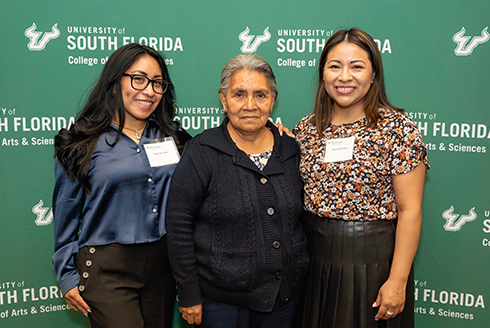 Cielo Gomez with her mom and another person smiling with a green usf Bulls background