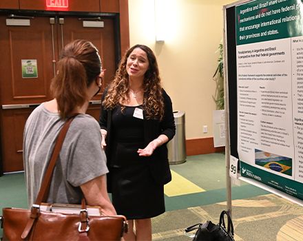 a woman explaining her research in front of a board with research papers on it