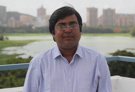 middle-aged India scholar smiles at the camera