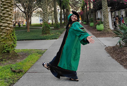 female Indian doctoral student in full regalia celbrating her graduation for the camera