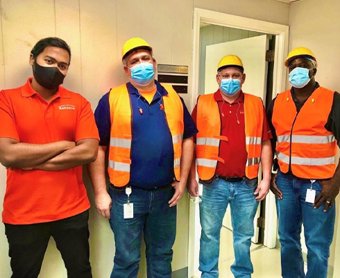 Khan standing with people wearing safety vests and hats