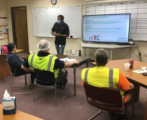 Khan teaching a group of people wearing safety vests