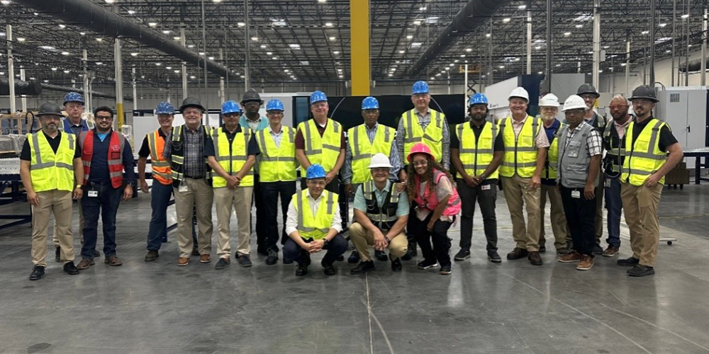 A group of people wearing safety gear in a large warehouse