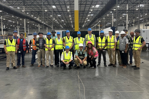 A group of people wearing safety gear in a large warehouse