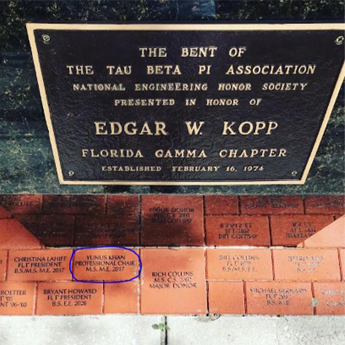 A brick with words engraved in it by the honors society statue