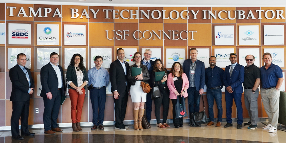 group shot of the Canada-Florida Chamber of Commerce with representatives from USF standing in front of the USF Technology Incubator CONNECT wall