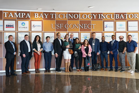 group shot of the Canada-Florida Chamber of Commerce with representatives from USF standing in front of the USF Technology Incubator CONNECT wall