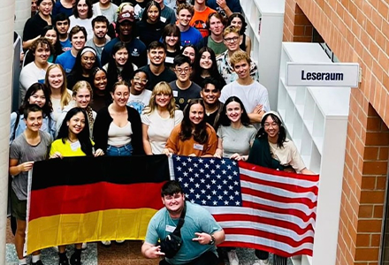 A group of students standing behind an American and German flag