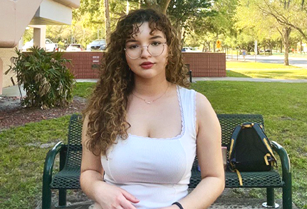 international student Anna sits on a bench and poses for the camera