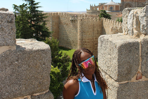 A student posing by the all of a castle