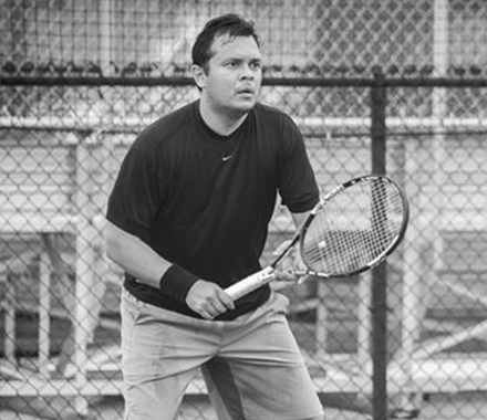 an alumnus playing tennis